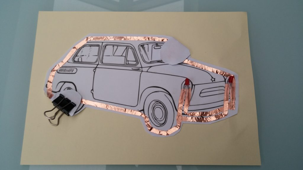 Car on paper with bronze conductive tape around it.